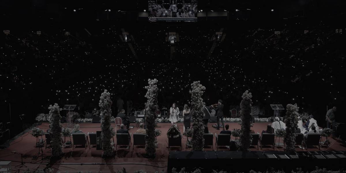 conference speakers on a stage with full arena